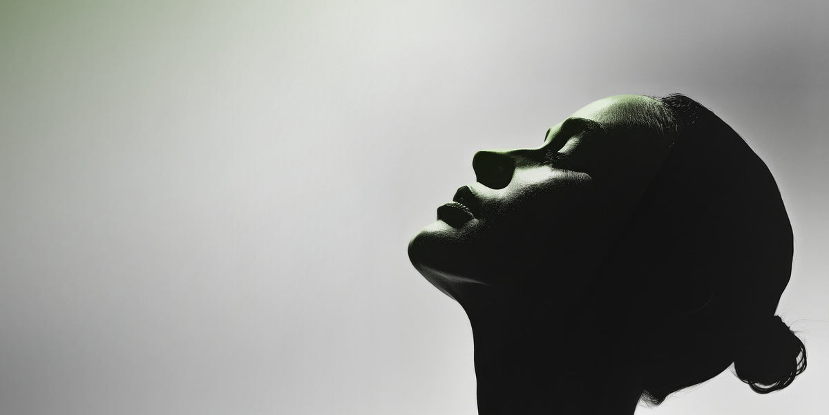 Silhouetted profile of a woman with hair in a bun against a soft gradient background