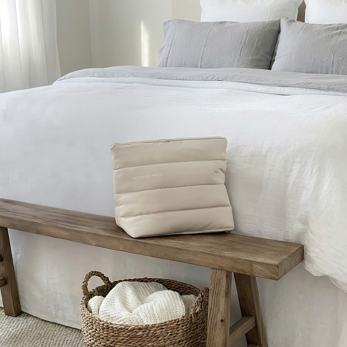 Large cream luxury device bag with quilted design on wooden bench in neutral bedroom